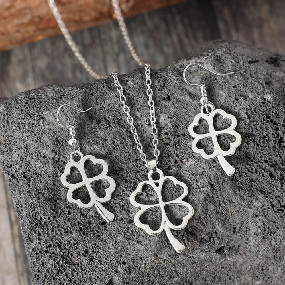 Lucky clover jewelry set featuring earrings and necklace on a rocky surface.
