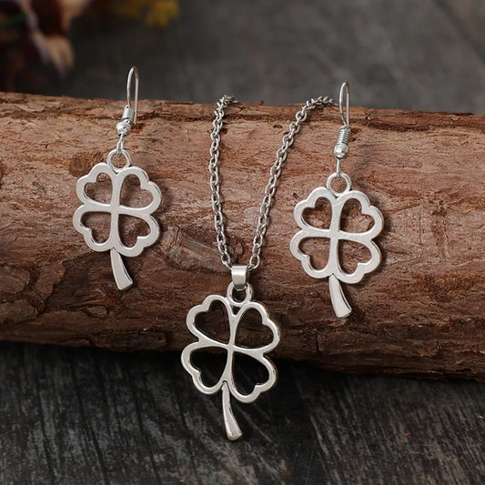 lucky clover jewelry set featuring silver earrings and necklace on a rustic wooden background.